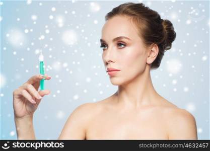 health, people, cosmetology, plastic surgery and beauty concept - beautiful young woman holding syringe with injection over blue background and snow