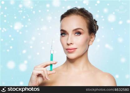 health, people, cosmetology, plastic surgery and beauty concept - beautiful young woman holding syringe with injection over blue background and snow