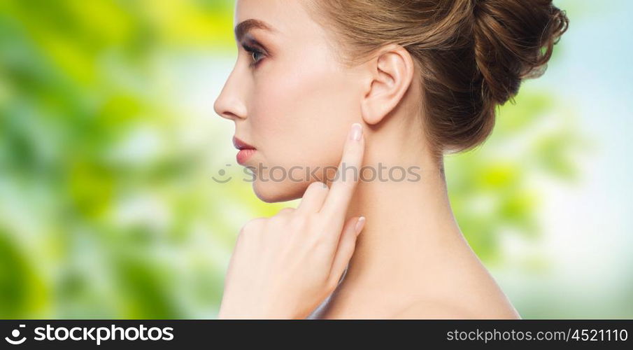 health, people, eco and beauty concept - beautiful young woman pointing finger to her ear over green natural background