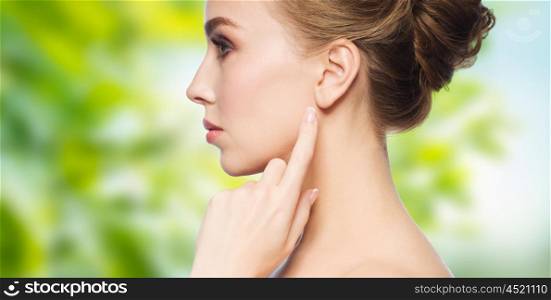 health, people, eco and beauty concept - beautiful young woman pointing finger to her ear over green natural background