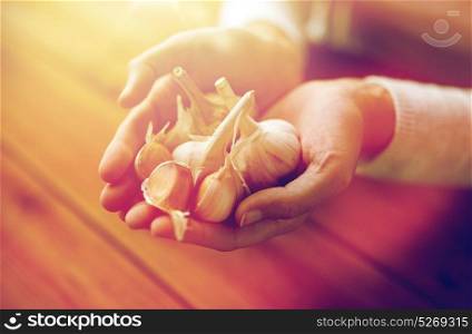 health, people, food, traditional medicine and ethnoscience concept - woman hands holding garlic for cooking or healing. woman hands holding garlic