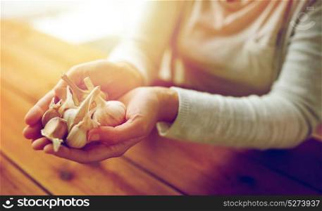 health, people, food, traditional medicine and ethnoscience concept - woman hands holding garlic for cooking or healing. woman hands holding garlic