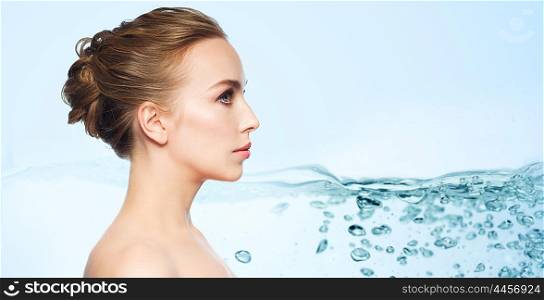 health, people, plastic surgery and beauty concept - beautiful young woman face over water splash bubbles on blue background