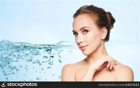 health, people, plastic surgery and beauty concept - beautiful young woman face over water splash bubbles on blue background