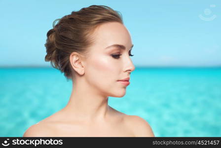 health, people, plastic surgery and beauty concept - beautiful young woman face over blue sea and sky background