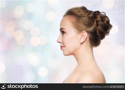 health, people, plastic surgery and beauty concept - beautiful young woman face over blue holidays lights background