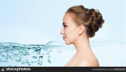 health, people, plastic surgery and beauty concept - beautiful young woman face over blue background with water splash