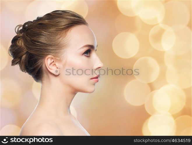 health, people, plastic surgery and beauty concept - beautiful young woman face profile over holidays lights background