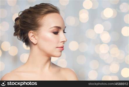 health, people, plastic surgery and beauty concept - beautiful young woman face over holidays lights background