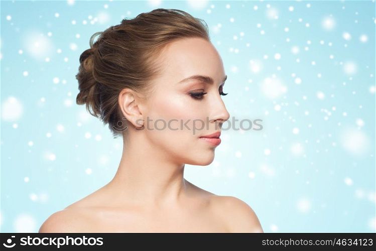 health, people, winter, plastic surgery and beauty concept - beautiful young woman face over blue background and snow