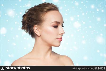 health, people, winter, plastic surgery and beauty concept - beautiful young woman face over blue background and snow