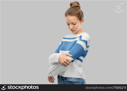 health problem and people concept - teenage girl having pain in hand over grey background. teenage girl having pain in hand