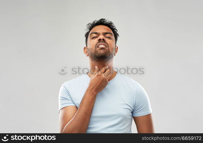 health problem and people concept - unhealthy indian man suffering from neck pain or sore throat over grey background. indian man suffering from neck pain or sore throat