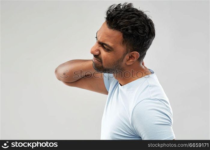 health problem and people concept - unhealthy indian man suffering from neck pain over grey background. unhealthy indian man suffering from neck pain