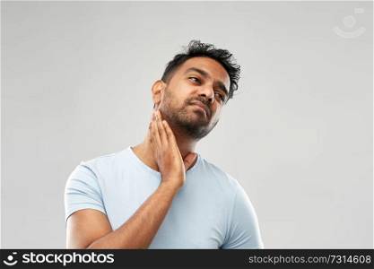 health problem and people concept - unhealthy indian man suffering from sore glands or tonsils over grey background. indian man suffering from sore glands or tonsils