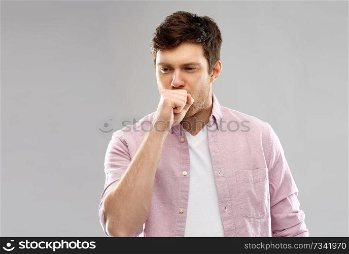 health problem and people concept - unhealthy young man coughing over grey background. unhealthy young man coughing