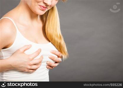 Health problem concept. Young woman feel menstrual cyclic breast pain touching her chest on gray. Woman suffering from breast pain