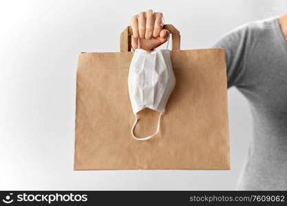 health protection, safe shopping and pandemic concept - close up of woman with paper bag for takeaway food and face protective medical mask. woman with shopping bag and face protective mask