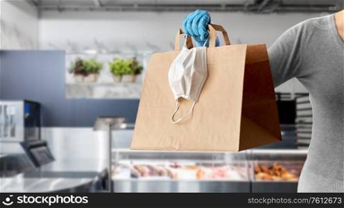 health protection, safe shopping and pandemic concept - close up of woman with paper bag, face protective medical mask and glove over grocery store on background. woman with food in paper bag, face mask and gloves