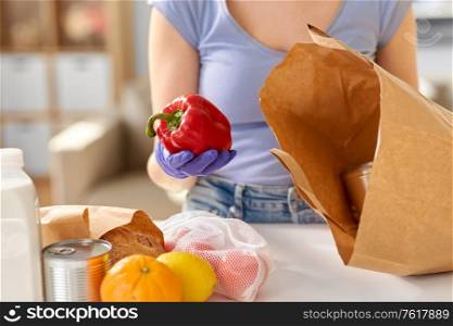 health protection, safety and pandemic concept - close up of woman in protective medical gloves taking food from paper bag at home. woman in gloves taking food from paper bag at home