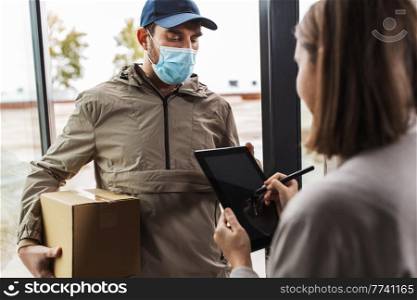 health protection, safety and pandemic concept - delivery man in face protective mask with parcel box and female customer signing digital form on tablet pc computer at home. deliveryman in mask and woman signing digital form