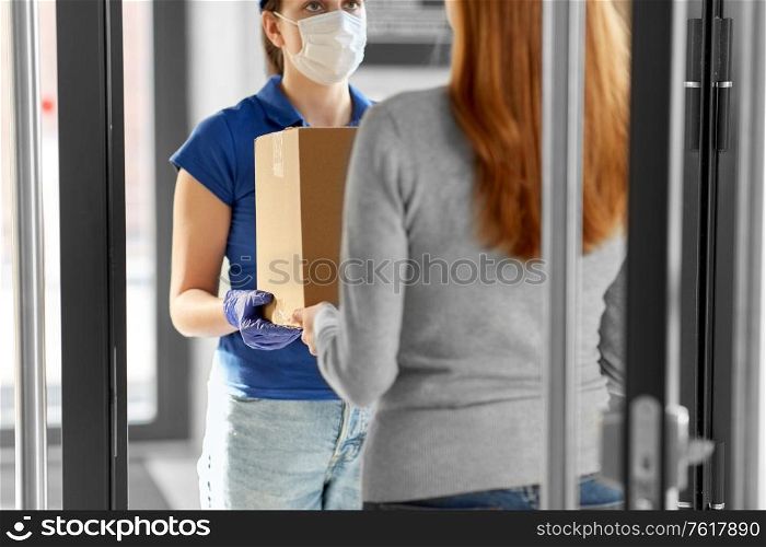 health protection, safety and pandemic concept - delivery woman in face protective mask and gloves giving parcel box to female customer at office. delivery girl in face mask giving parcel to woman