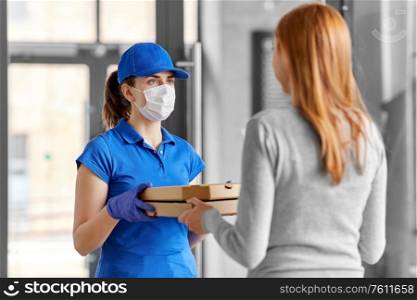 health protection, safety and pandemic concept - delivery woman in medical face mask and gloves giving pizza boxes to female customer at office. delivery girl in mask giving pizza boxes to woman