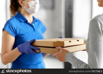 health protection, safety and pandemic concept - delivery woman in medical face mask and gloves giving pizza boxes to female customer at office. delivery girl in mask giving pizza boxes to woman