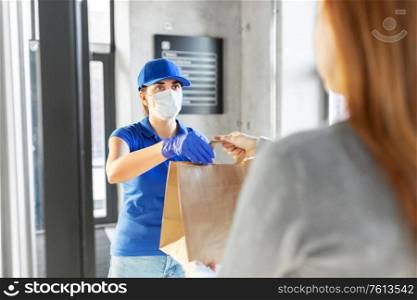 health protection, safety and pandemic concept - delivery woman in protective face mask and gloves giving paper bag with food to female customer at office. delivery girl in mask giving paper bag to customer