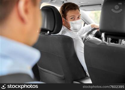 health protection, safety and pandemic concept - male taxi driver wearing face protective medical mask driving car with passenger. taxi driver in face protective mask driving car