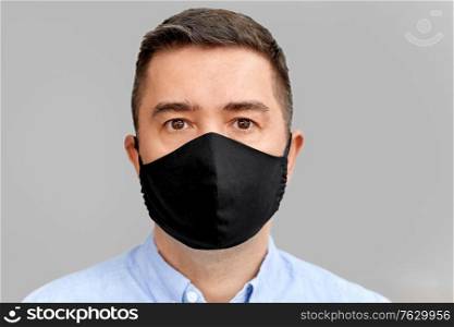 health protection, safety and pandemic concept - portrait of middle-aged man in black reusable face protective mask over grey background. middle-aged man in reusable face protective mask