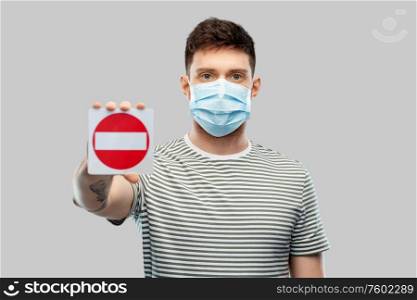 health protection, safety and pandemic concept - young man in protective medical mask showing stop sign over grey background. young man girl in medical mask showing stop sign
