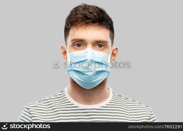 health protection, safety and pandemic concept - young man in protective medical mask over grey background. young man in protective medical mask