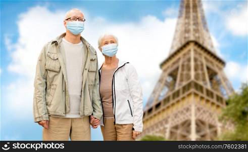 health, quarantine and pandemic concept - senior couple wearing protective medical mask for protection from virus holding hands over eiffel tower in paris, france background. old couple in protective medical masks in france