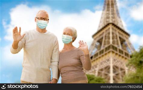 health, quarantine and pandemic concept - senior couple wearing protective medical mask for protection from virus holding hands over eiffel tower in paris, france background. old couple in protective medical masks in france