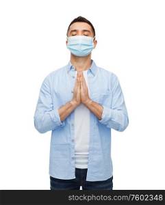 health, quarantine and pandemic concept - young man wearing protective medical mask for protection from virus disease praying over grey background. young man in protective medical mask praying