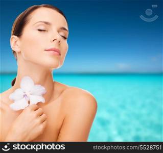 health, relaxation and beauty concept - relaxed woman with orhid flower