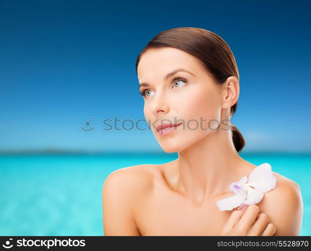 health, relaxation and beauty concept - relaxed woman with orhid flower