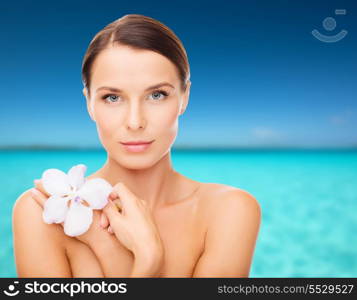 health, relaxation and beauty concept - relaxed woman with orhid flower