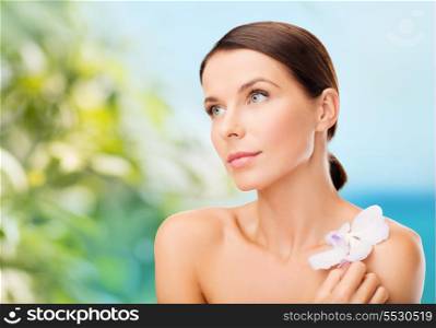 health, relaxation and beauty concept - relaxed woman with orhid flower