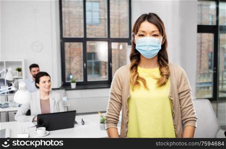 health, safety and pandemic concept - asian young woman wearing protective medical mask for protection from virus disease over office background. asian woman in protective medical mask at office