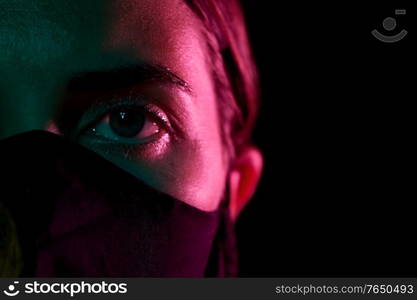 health, safety and pandemic concept - close up of young woman wearing reusable protective mask over black background. young woman wearing reusable protective mask