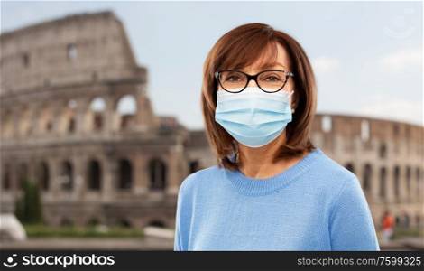 health, safety and pandemic concept - portrait of senior woman in glasses wearing protective medical mask for protection from virus over coliseum in rome, italy background. senior woman in protective medical mask in italy