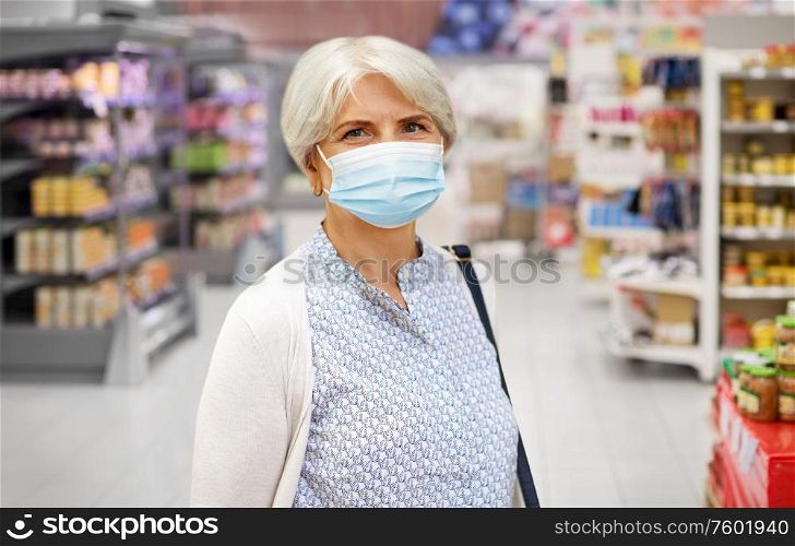 health, safety and pandemic concept - portrait of senior woman in glasses wearing protective medical mask for protection from virus over supermarket background. senior woman in medical mask at supermarket