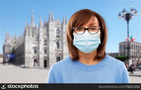 health, safety and pandemic concept - portrait of senior woman in glasses wearing protective medical mask for protection from virus over milano cathedral in rome, italy background. senior woman in protective medical mask in italy