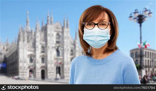 health, safety and pandemic concept - portrait of senior woman wearing protective medical mask for protection from virus over milano cathedral in rome, italy background. senior woman in protective medical mask in italy