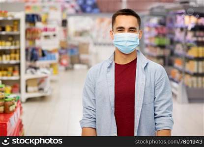 health, safety and pandemic concept - young man wearing protective medical mask for protection from virus over supermarket background. young man in medical mask at supermarket