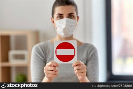health, safety and pandemic concept - young woman in protective medical mask showing stop sign at home. woman in protective medical mask showing stop sign