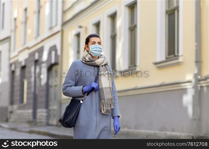 health, safety and pandemic concept - young woman wearing protective medical mask on empty street of old town in tallinn city. young woman wearing protective medical mask