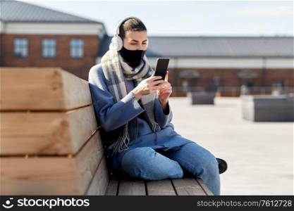 health, safety and pandemic concept - young woman wearing protective medical mask and using smartphone on city street. woman in face mask with smartphone in city